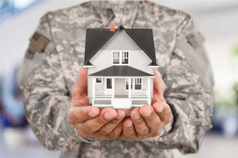 Military Veteran in uniform holding a small model home